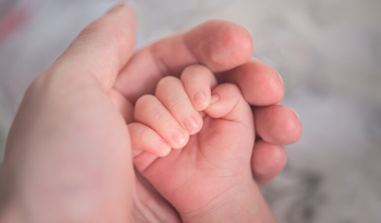 person holding baby's hand in close up photography
